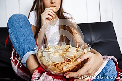 Young pretty girl watching tv, sitting on sofa at home. Stock Photo