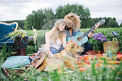 Young pretty hippie couple with guitar and dog outdoor Stock Photo