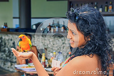 Young pretty indian girl with long black curly hair feeding of sugar to wild parrot that living in tropical jungle on exotic islan Editorial Stock Photo