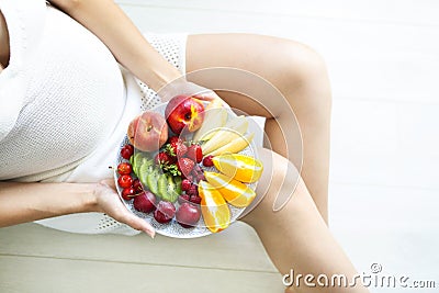 Young pretty pregnant woman with fruit plate Stock Photo