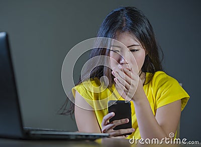 Young pretty shocked and surprised Asian Korean woman looking stressed at mobile phone feeling worried and scared in cyber bullyin Stock Photo
