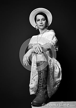 Young pretty short haired brunette woman in white elegant dress boots and hat sitting looking at camera Stock Photo