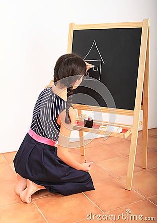 Girl drawing house on black blackboard Stock Photo