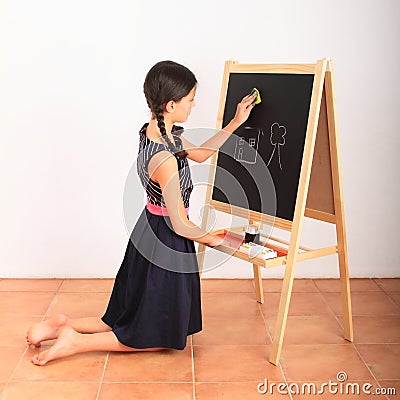 Girl erasing house and tree from black blackboard Stock Photo