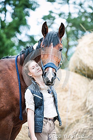 Young pretty teenage girl equestrian hugs her favorite horse Stock Photo