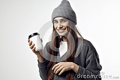 Young pretty woman in a grey outfit with a paper cup of coffee. Take away package for layout. Stock Photo