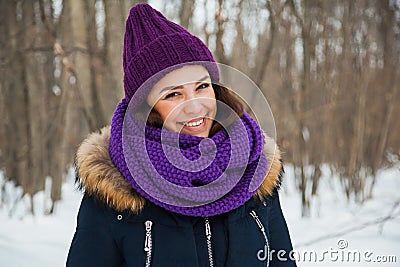 Young pretty woman with happy smile in purple snood and hand-knitted hat. Stock Photo