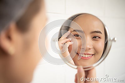 Pretty women are looking at the mirror to see the facial wrinkles. Stock Photo