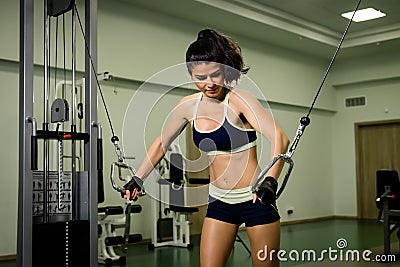 Young pretty woman pumping up muscles with training apparatus Stock Photo
