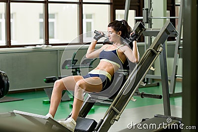 Young pretty woman pumping up muscles with training apparatus Stock Photo