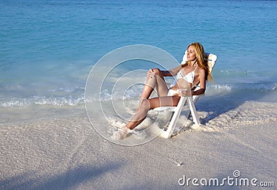 Young pretty woman tans in beach chair in sea Stock Photo