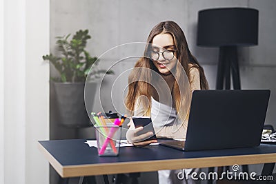 Young professional doing creative project on laptop. Girl sitting by computer at office desk. Digital tools and solutions for Stock Photo