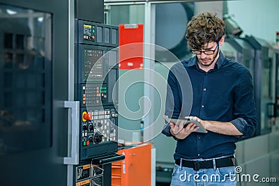 young professional engineer male working programming automatic CNC machine in automation metal factory Stock Photo