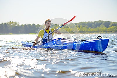 Young Professional Kayaker Paddling Kayak on River under Bright Morning Sun. Sport and Active Lifestyle Concept Stock Photo