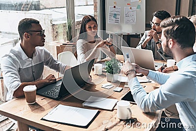 Young professional team. Top view of young modern people in smart casual wear discussing business while working in the creative o Stock Photo