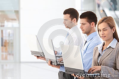 Young professionals using laptop in office lobby Stock Photo