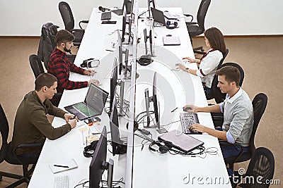 Young professionals working in modern office. Group of developers or programmers sitting at desks focused on computers Stock Photo