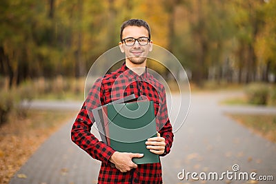 Young professor in glasses holding folders in autumn park Stock Photo