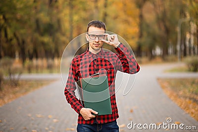 Young professor in glasses holding folders in autumn park Stock Photo