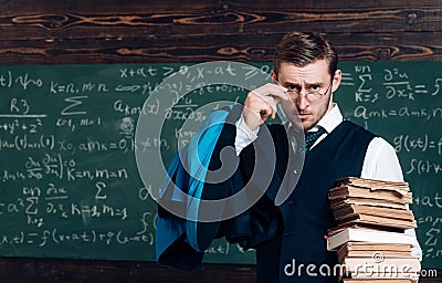 Young professor holding pile of books looking over his glasses. Aristocrat scholar in elite college Stock Photo