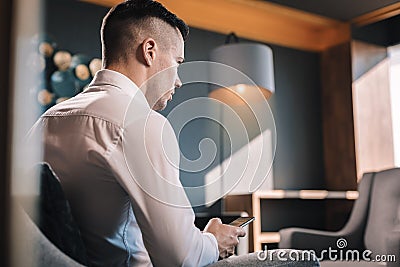 Young but prosperous businessman sitting in his office using phone Stock Photo