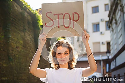 Young protesting woman in white shirt and jeans holds protest sign broadsheet placard with slogan `Stop` for public demonstratio Stock Photo