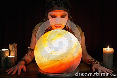 Young Psychic is telling the future, crystal ball and candles in Stock Photo