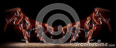 Young purposeful basketball player training in action isolated on black background with fire flames. Mirror, strobe Stock Photo