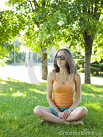 A young and quiet girl sitting in the grass. Stock Photo