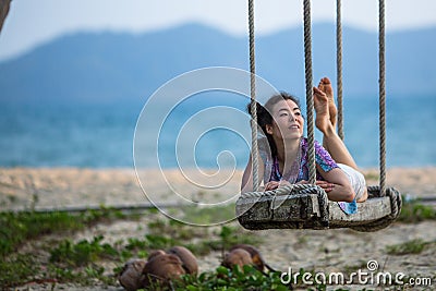 Young race woman lies on the swings on sea beach. Stock Photo