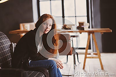 young readhead woman relaxing at home on cozy couch, dressed in casual sweater and jeans Stock Photo