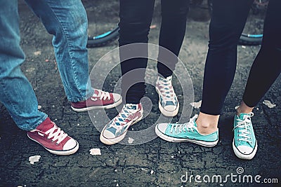 Young rebel teenagers wearing casual sneakers, walking on dirty concrete. Canvas shoes and sneakers on female adults Stock Photo