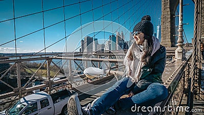 Young and reckless girl sits on the rim of Brooklyn Bridge New York Stock Photo