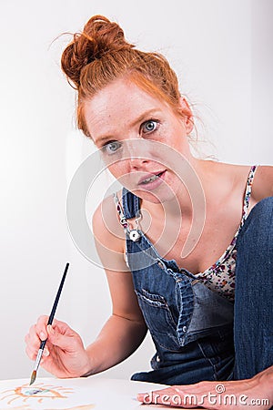 Young red-haired woman paints in her spare time Stock Photo