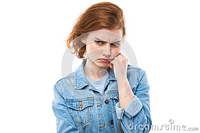 The young red-haired woman pondered. Resentment and disappointment. Girl model in a blue denim jacket on a white background. I Stock Photo