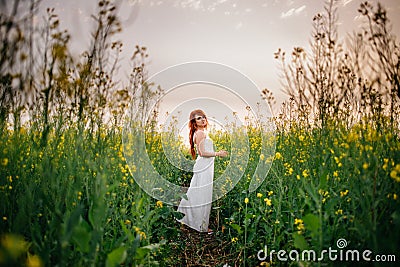 Young red-haired woman in a rapeseed field Stock Photo