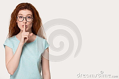 Red-haired woman in glasses aside free space show hush gesture Stock Photo