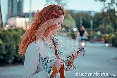 Young redhaired woman standing at night with phone Stock Photo