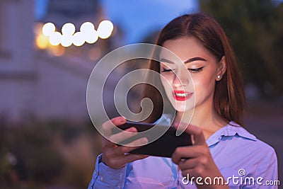 Young redhead businesswoman communicating by smartphone at evening in city Stock Photo