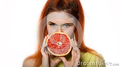 Young redhead woman with a grapefruit on a white background. concept of healthy eating Stock Photo