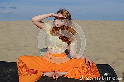 Young redhead woman sitting in purna titli yoga pose on the beach Stock Photo