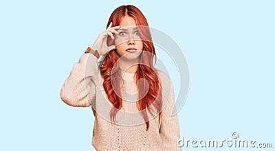Young redhead woman wearing casual winter sweater worried and stressed about a problem with hand on forehead, nervous and anxious Stock Photo