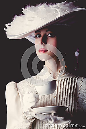 Woman in white Victorian era clothes with cup of tea Stock Photo