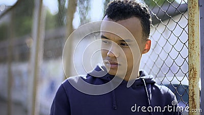 Young refugee from dysfunctional family leaning on fence, orphan teenager Stock Photo