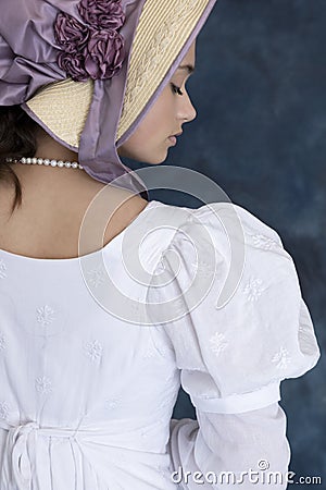 A young Regency woman wearing a white muslin dress, straw bonnet, and a pearl necklace Stock Photo