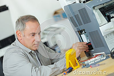 Young repairer working with screwdriver in service center Stock Photo