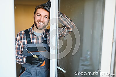 Young repairman adjusting a terrace door handle with screwdriver Stock Photo