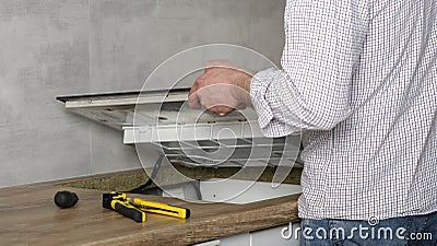 A young repairman installs a black induction hob in a modern white Scandinavian style kitchen Stock Photo