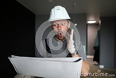 Young repairman standing in empty flat, looking at construction plan and feeling shocked Stock Photo