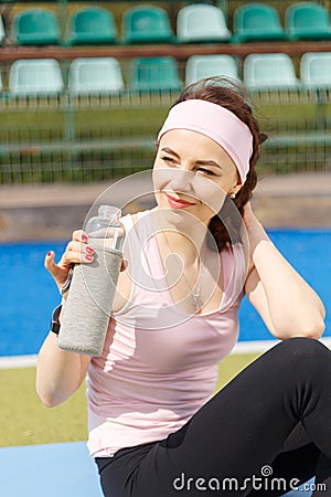 Young resting sportswoman holding bottle of water Stock Photo